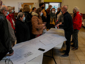 Arnaud Laforge, cadre de Noréade, explique au public les futurs travaux, les plans détaillés sont étalés sur une table, face à lui